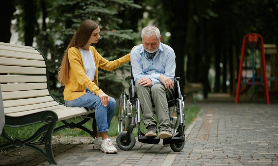 Woman takes care of disabled father in wheelchair